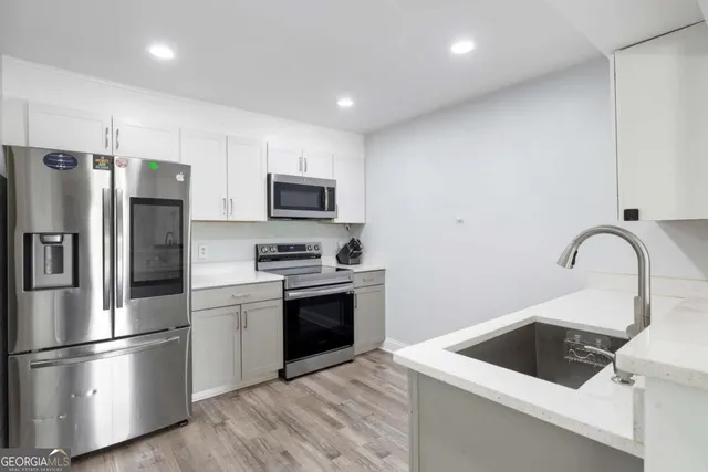 a kitchen with a sink white stainless steel appliances and cabinets