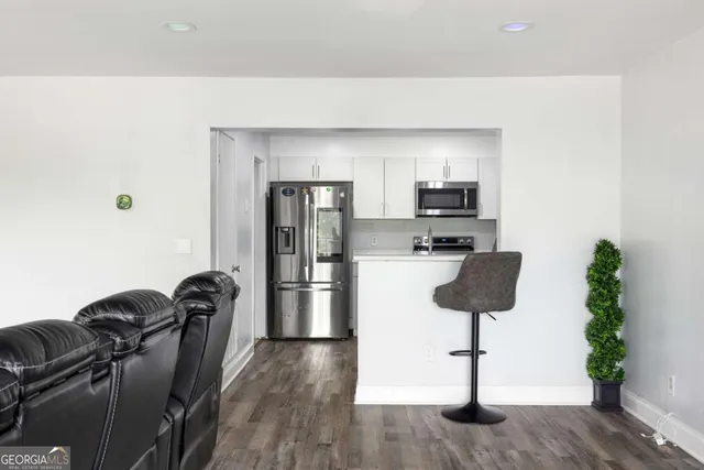 a kitchen with a refrigerator wooden floor a dining table and chairs