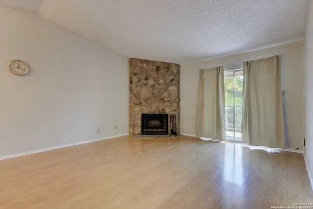 a view of an empty room with a window and fireplace