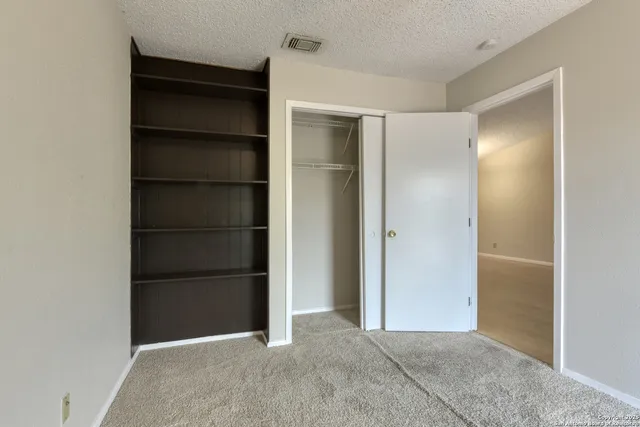 a view of an empty room with cabinet and door