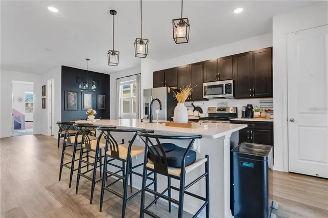 a kitchen with stainless steel appliances a table chairs refrigerator and microwave