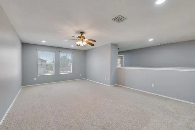 an empty room with windows and chandelier fan
