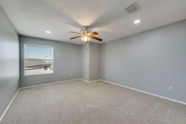 an empty room with a window and a fan
