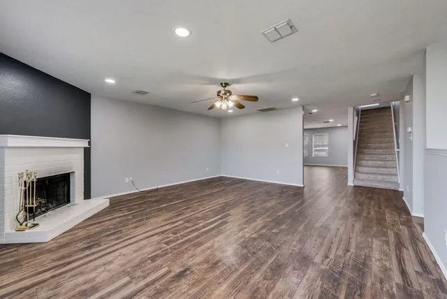 a view of an empty room with wooden floor and a fireplace
