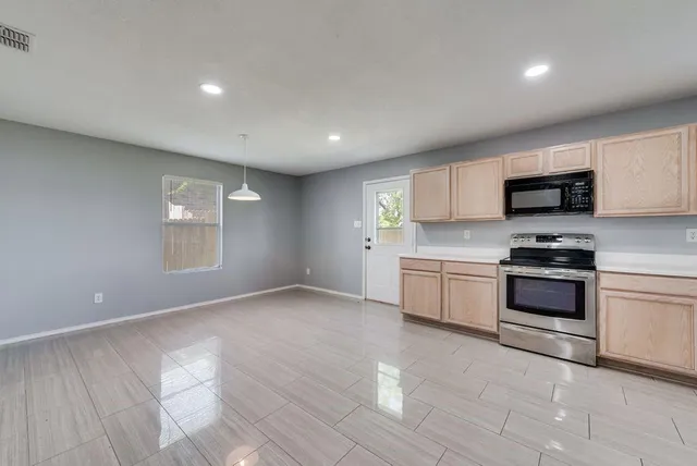 a kitchen with granite countertop a stove a sink and a microwave