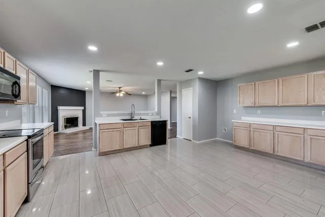 a large kitchen with cabinets wooden floor and stainless steel appliances