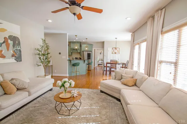 a dining hall with stainless steel appliances kitchen island granite countertop a refrigerator a sink a stove and a dining table with wooden floor