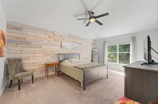 an empty room with wooden floor chandelier fan and windows