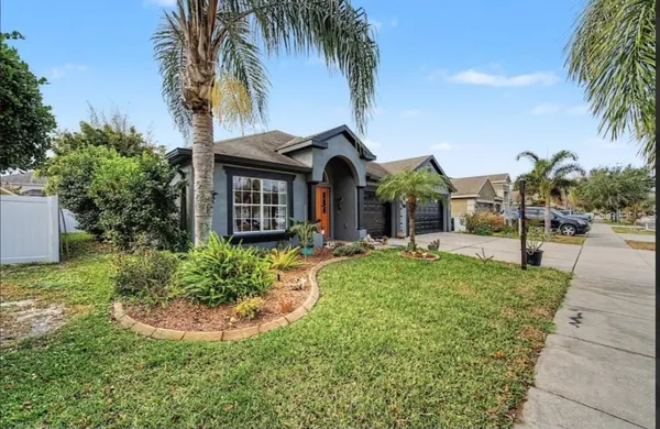 a view of a house with a yard and palm trees