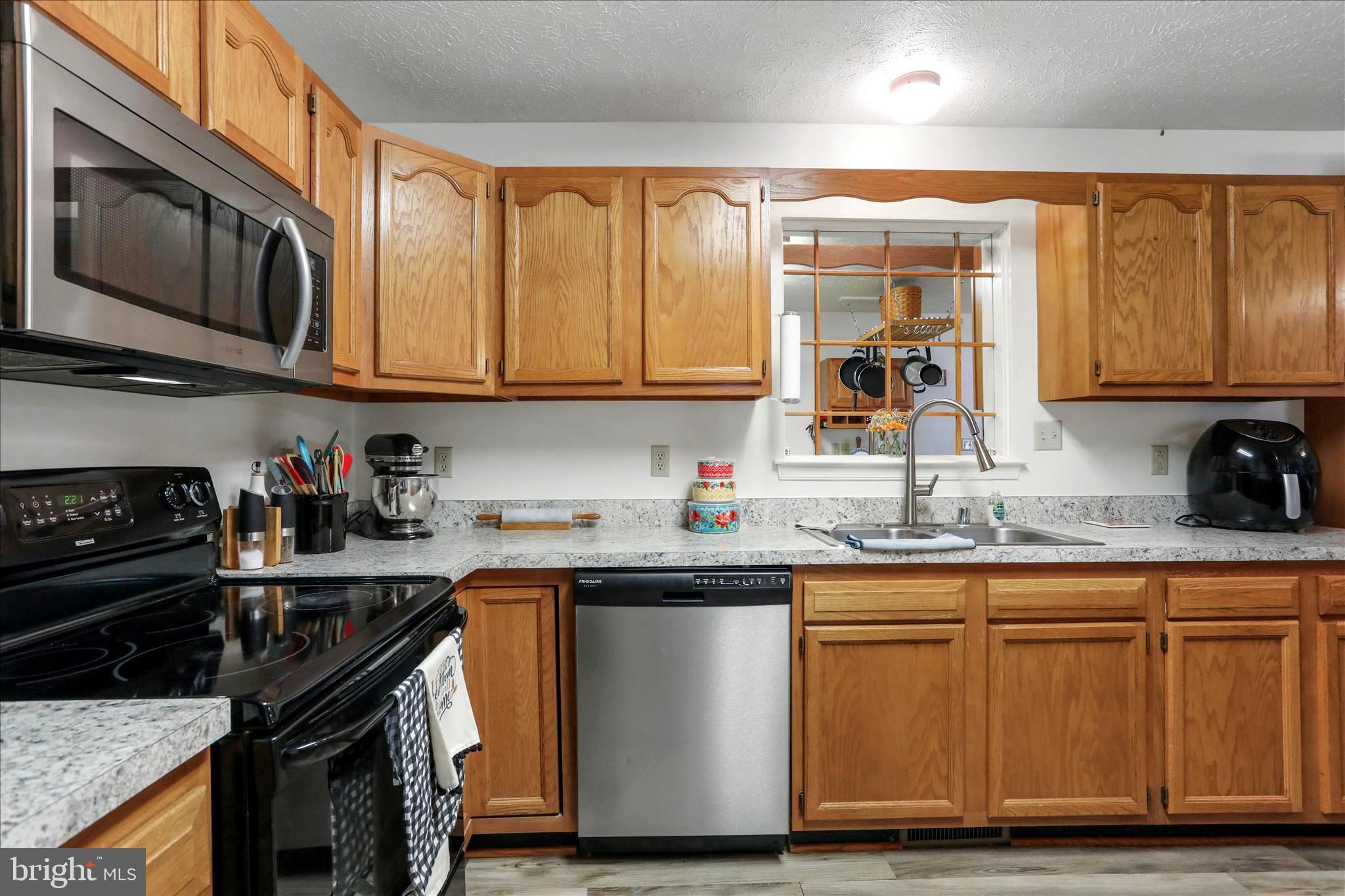 573 Lewis Street Front Royal, VA 22630 - Photo 12 of 45 a kitchen with stainless steel appliances granite countertop a stove a sink dishwasher and a microwave oven with wooden cabinets