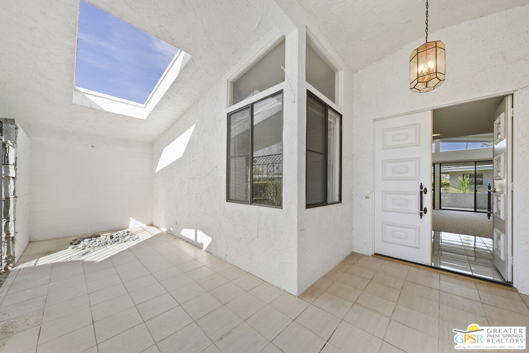 2296 Paseo Del Rey Palm Springs, CA 92264 - Photo 3 of 42 a view of an empty room with wooden floor and chandelier