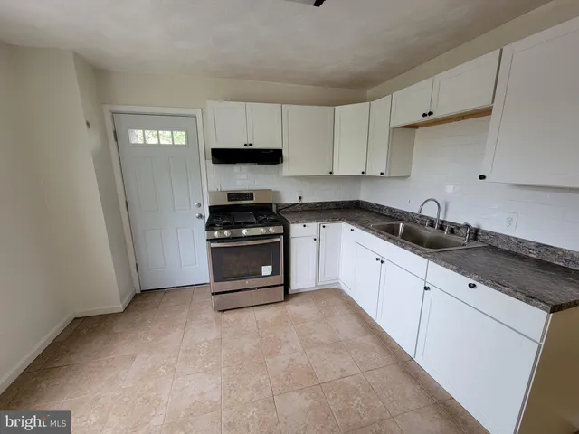 a kitchen with stainless steel appliances granite countertop a stove a sink and a white cabinets