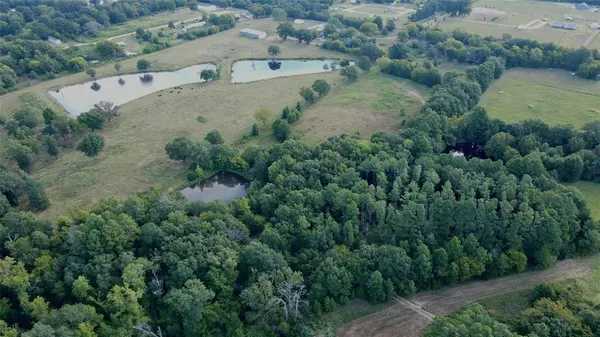 an aerial view of residential house with outdoor space and trees all around