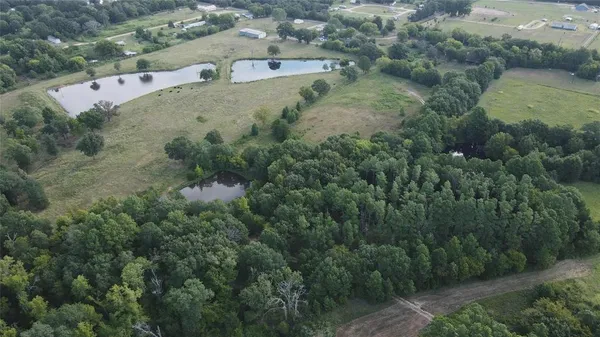 an aerial view of residential house with outdoor space and trees all around