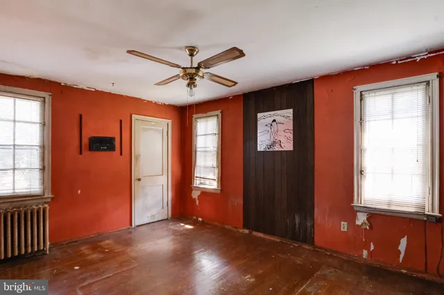 an empty room with windows and ceiling fan