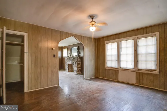 an empty room with chandelier fan and windows