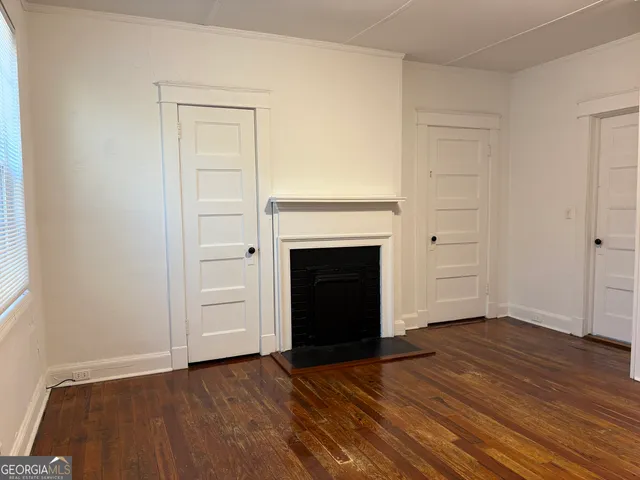 an empty room with wooden floor a fireplace and windows