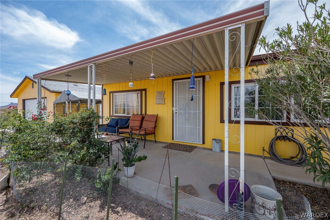 2465 Egar Road Golden Valley, AZ 86413 - Photo 13 of 98 The property features a yellow exterior with white trim windows and a covered concrete patio