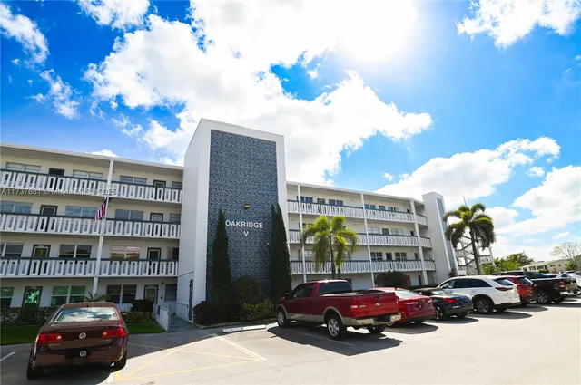 a view of a building with a big yard and large trees
