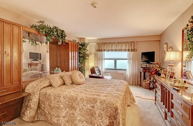 a bedroom with a bed a flat screen tv and a large window