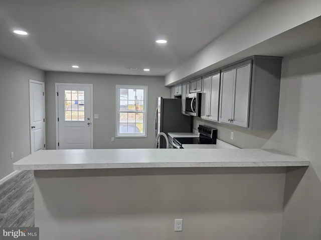 a view of kitchen island a sink wooden floor and living room view