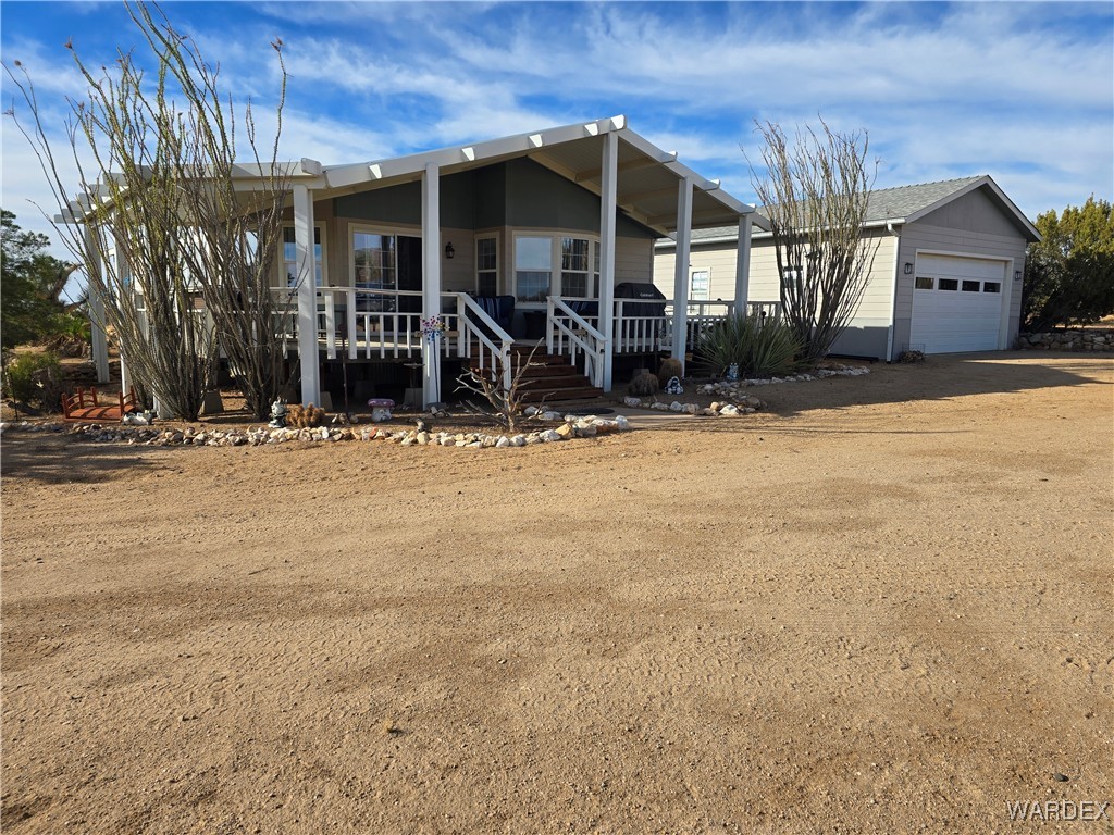 19688 South Diamondback Road Yucca, AZ 86438 - Photo 1 of 66 View of front of house with a garage and covered porch. 40 Acre Homestead with Solar and Well.