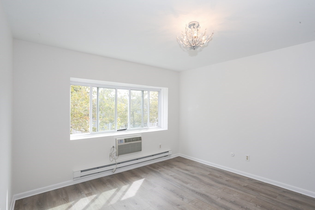 461 Washington Street, Unit 301 Boston, MA 02135 - Photo 4 of 13 an empty room with wooden floor and windows