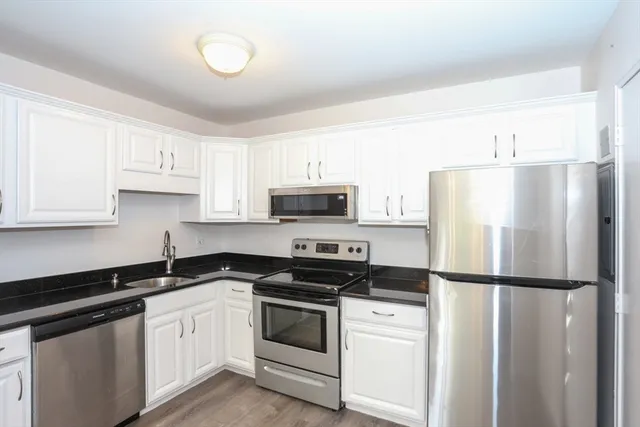 a kitchen with white cabinets sink and stainless steel appliances