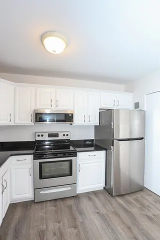 a kitchen with a sink a white refrigerator and white cabinets