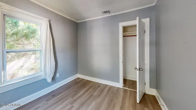 an empty room with wooden floor and windows