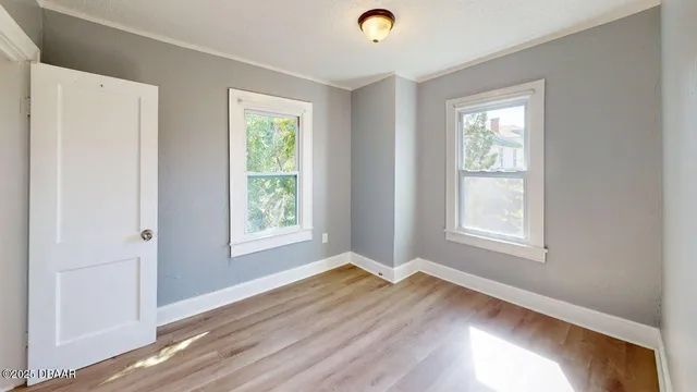 a view of an empty room with wooden floor and a window
