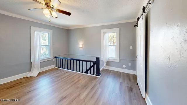 a view of an empty room with wooden floor and a window