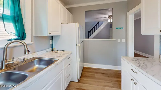 a kitchen with granite countertop a sink dishwasher a stove and white cabinets with wooden floor