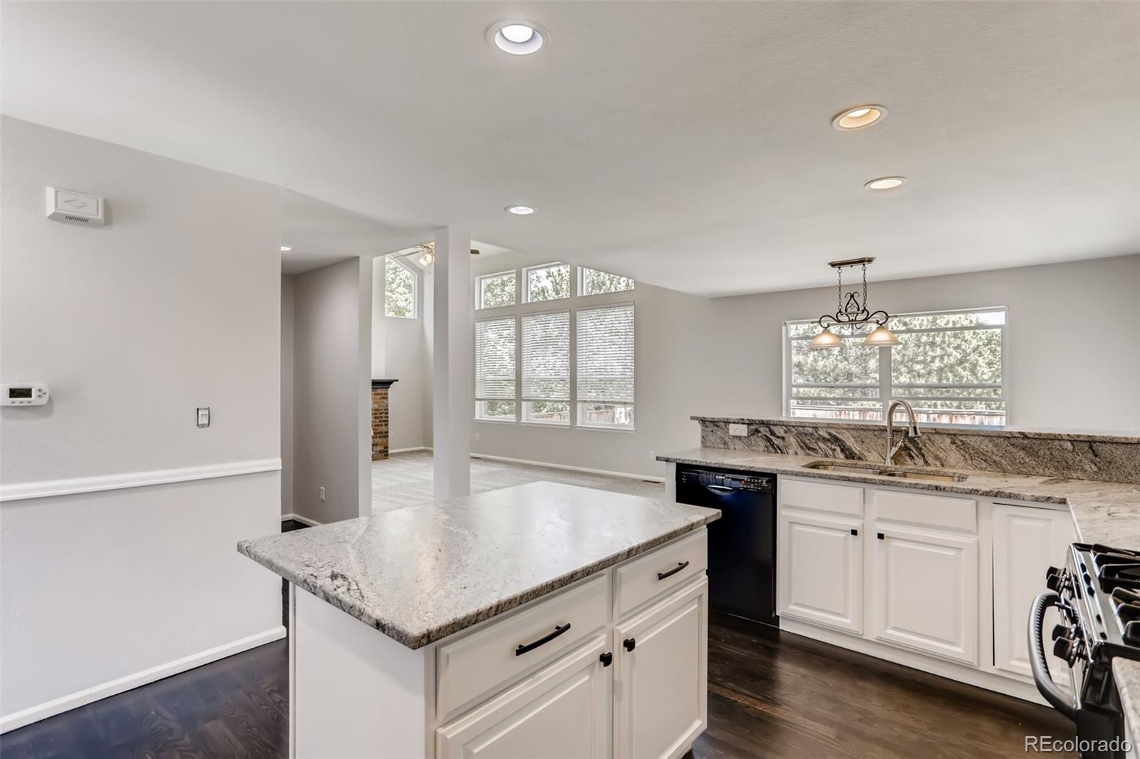 1639 Spring Water Lane Highlands Ranch, CO 80129 - Photo 14 of 39 a kitchen with granite countertop a stove a sink a refrigerator and white cabinets with wooden floor