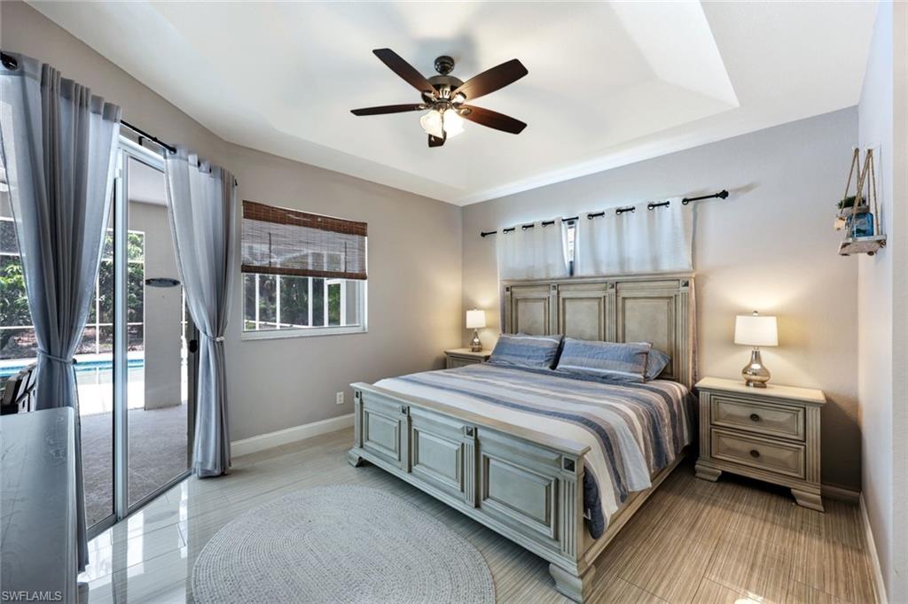 697 Crossfield Circle Naples, FL 34104 - Photo 11 of 18 Bedroom with access to exterior, a tray ceiling, and a ceiling fan