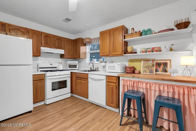 a kitchen with stainless steel appliances granite countertop a stove a sink dishwasher and a refrigerator with wooden cabinets