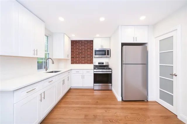 a kitchen with a refrigerator a sink and dishwasher with wooden floor