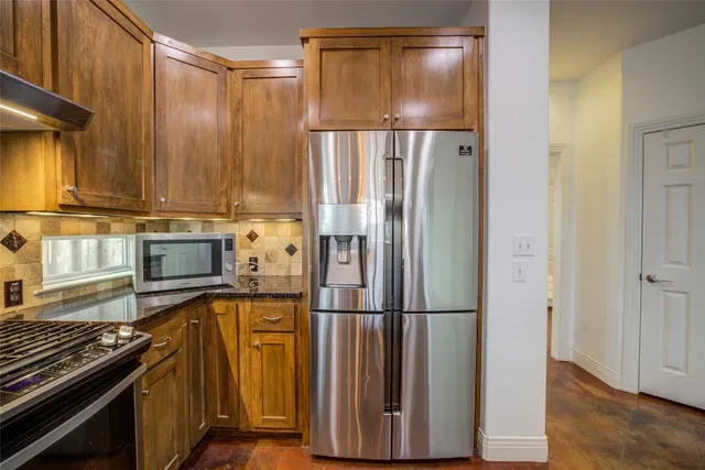a kitchen with stainless steel appliances granite countertop a refrigerator and a stove top oven