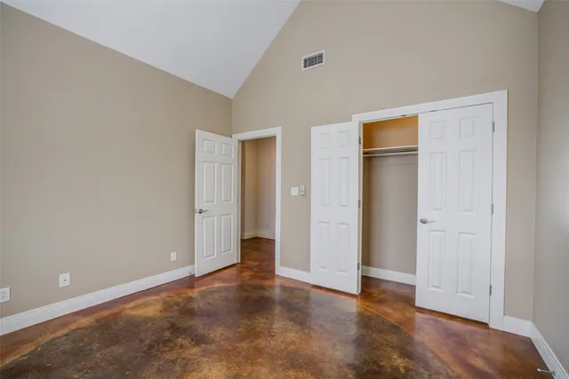a view of an empty room with wooden floor and closet