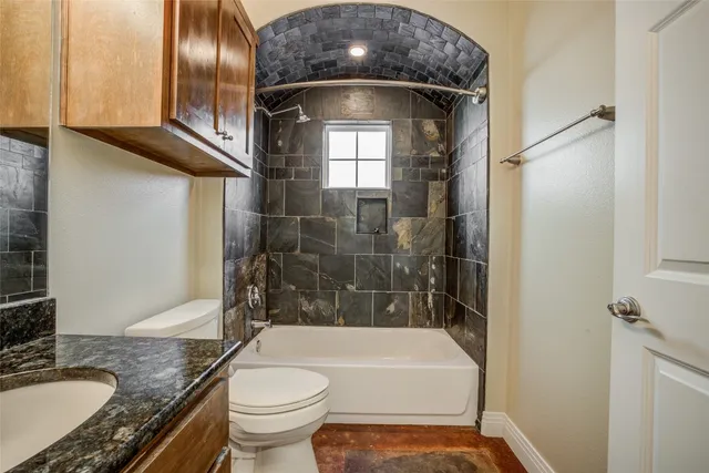 a bathroom with a granite countertop toilet sink and mirror