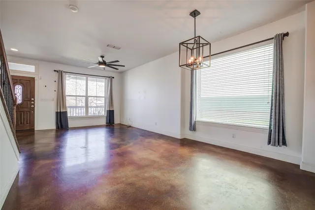 an empty room with wooden floor chandelier and windows