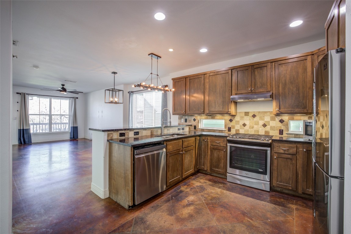 4109 East 12th Street, Unit 2 Austin, TX 78721 - Photo 9 of 39 a kitchen with stainless steel appliances granite countertop a stove top oven a sink dishwasher a refrigerator and a dining table with wooden floor