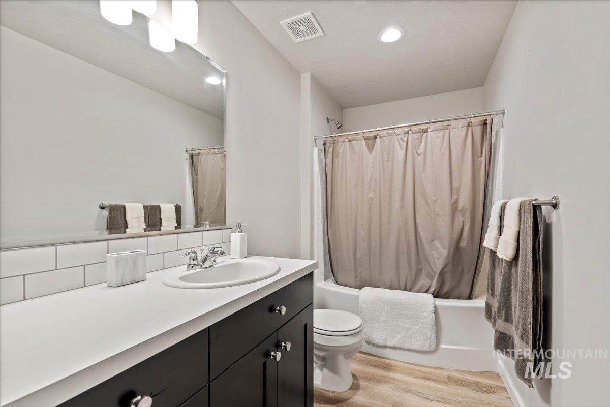 1211 Mahogany Street Parma, ID 83660 - Photo 23 of 30 Bathroom featuring vanity, wood finished floors, shower / bathtub combination with curtain, and recessed lighting