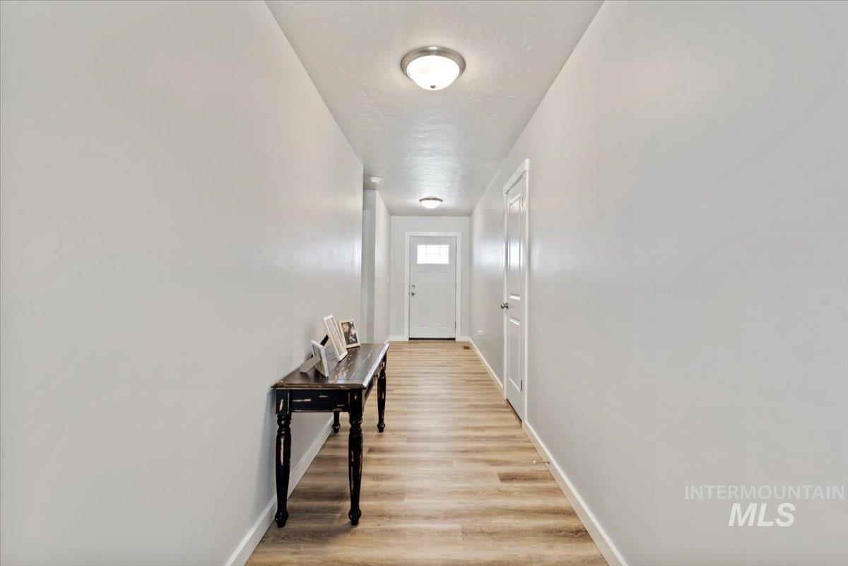 1211 Mahogany Street Parma, ID 83660 - Photo 4 of 30 Hallway featuring light wood-type flooring and a textured ceiling