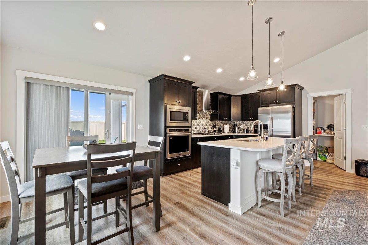 1211 Mahogany Street Parma, ID 83660 - Photo 9 of 30 Kitchen featuring backsplash, lofted ceiling, light countertops, appliances with stainless steel finishes, and light wood-type flooring