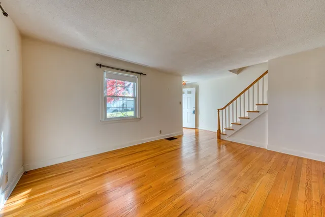 a view of an empty room with wooden floor and windows