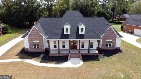 a aerial view of a house with yard and trees in the background