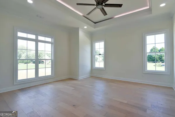 a view of an empty room with a window and wooden floor