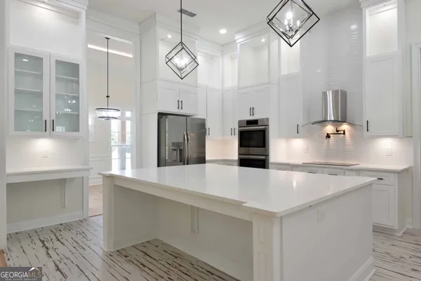 a large kitchen with stainless steel appliances a large counter top a refrigerator and a sink