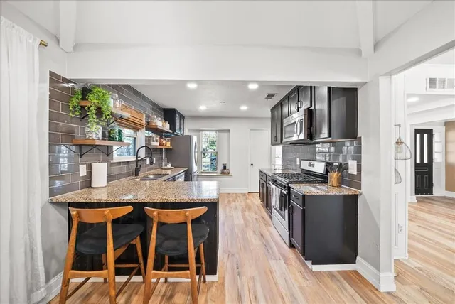 a kitchen with stainless steel appliances granite countertop table chairs and wooden floor